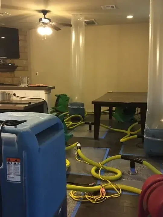 Dehumidifiers and coiled hoses stand in a room adjoining a kitchen